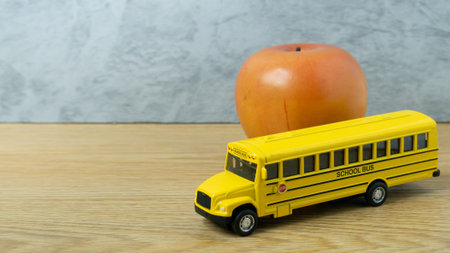 school bus toy and apple on wood table for back to school or education concept