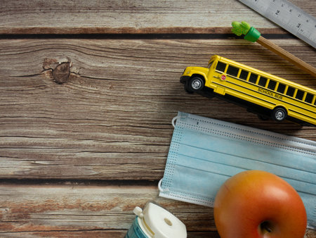 The school bus and mask on wood table for education  or medical  concept