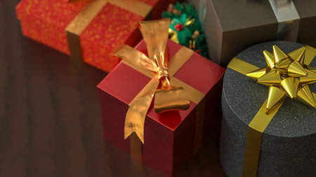 Festive Christmas gift boxes with golden ribbons and a small wreath on wooden table, creating a warm holiday celebration atmosphere.の写真素材