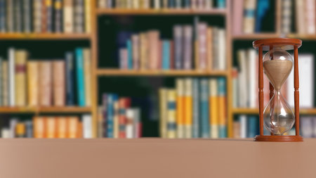 Vintage wooden hourglass placed on a table with a blurred library background, symbolizing time, study, knowledge, and focus.の写真素材