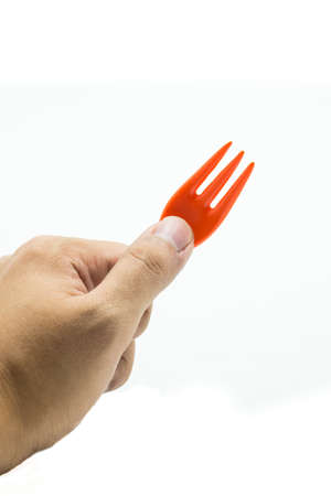 hand with orange fork isolated on white の写真素材
