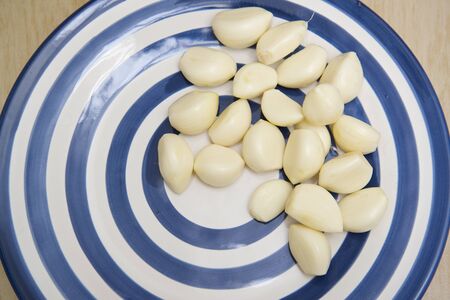 Peeled clove of garlic on blue and white plate Bangkok Thailandの写真素材