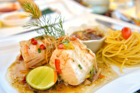 Steamed fish with spicy ginger sauce on white plateの写真素材