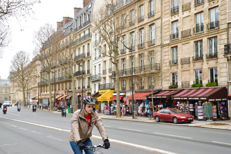 People are riding bike along the street passing many retails shop and restaurants in Paris, Franceのeditorial素材