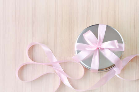 Gift in round tin box with pink ribbon backgroundの写真素材