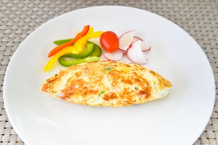 Egg white omelet with bell pepper, tomato and radish on white plateの写真素材