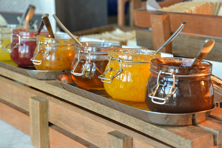 Varieties of jams in glass jars with spoonの写真素材