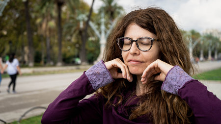 Beautiful girl with a purple hood and glasses and curly hair looking into the camera with both hands...