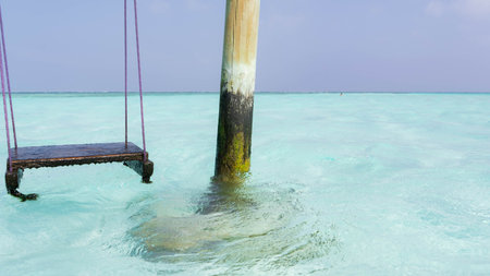 Swing and post over the sea in a beautiful paradise beach with turquoise waters and blue sky and clear waterの写真素材