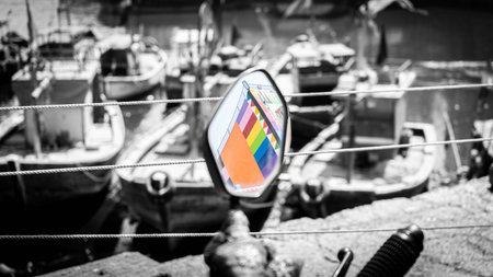 Colorful building reflection in a rearview mirror with boats and ships in black and white and out of focus in the backgroundの写真素材