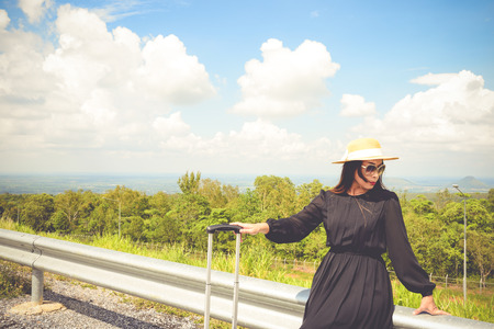 Women dressed in black with purple travel wallet,Traveling by road.の写真素材