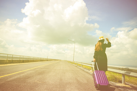 Women dressed in black with purple travel wallet,Traveling by road.の写真素材