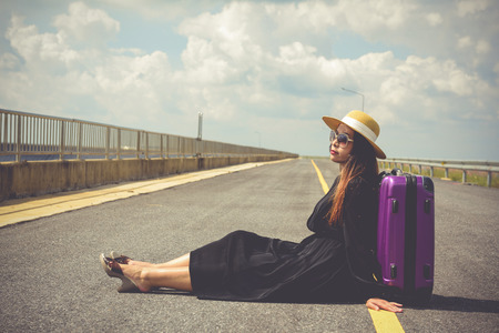 Women dressed in black with purple travel wallet,Traveling by road.の写真素材