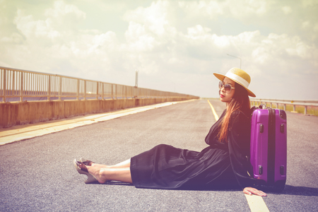 Women dressed in black with purple travel wallet,Traveling by road.の写真素材