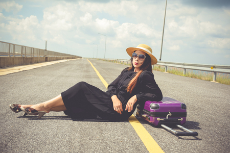 Women dressed in black with purple travel wallet,Traveling by road.の写真素材
