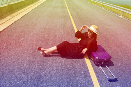 Women dressed in black with purple travel wallet,Traveling by road.の写真素材