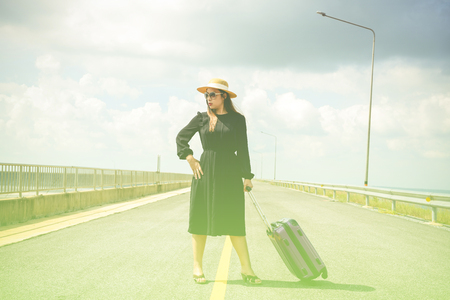 Women dressed in black with purple travel wallet,Traveling by road.の写真素材