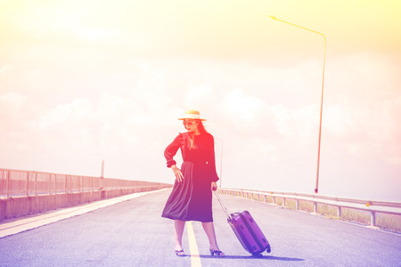 Women dressed in black with purple travel wallet,Traveling by road.の写真素材