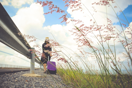 Women dressed in black with purple travel wallet,Traveling by road.の写真素材