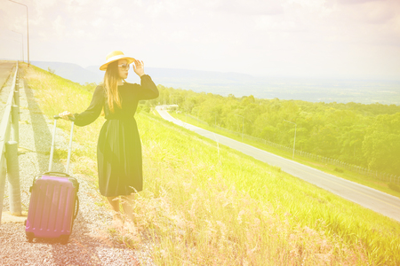 Women dressed in black with purple travel wallet,Traveling by road.の写真素材
