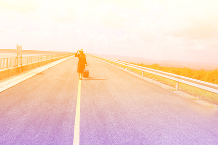 Women dressed in black with purple travel wallet,Traveling by road.の写真素材