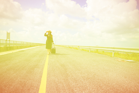 Women dressed in black with purple travel wallet,Traveling by road.の写真素材