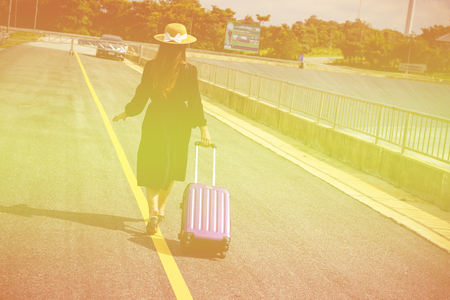 Women dressed in black with purple travel wallet,Traveling by road.の写真素材