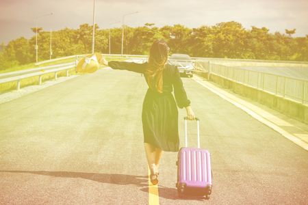 Women dressed in black with purple travel wallet,Traveling by road.の写真素材