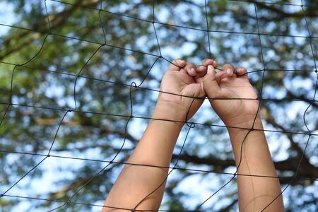 Hands with rope mesh fenceの写真素材