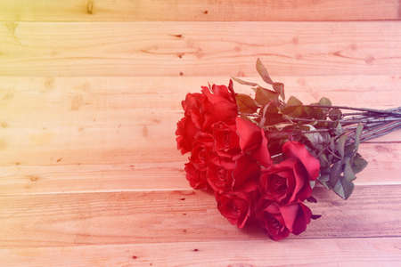 A bouquet of red roses on a wooden background.の写真素材