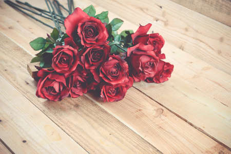 A bouquet of red roses on a wooden background.の写真素材