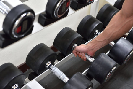 sport, bodybuilding, training and people concept , young man with dumbbell flexing muscles in...