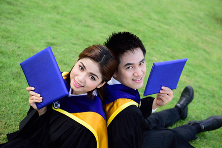 Happy graduated student guy and girl at graduation ceremonyの写真素材