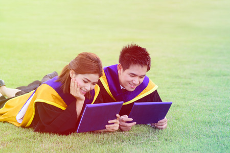 Happy graduated student guy and girl at graduation ceremonyの写真素材