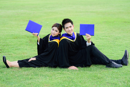 Happy graduated student guy and girl at graduation ceremonyの写真素材