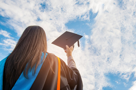 Graduates of the University,Of graduates holding hats handed to the sky.の写真素材