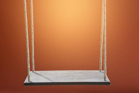 Wood swing on an orange backgroundの写真素材
