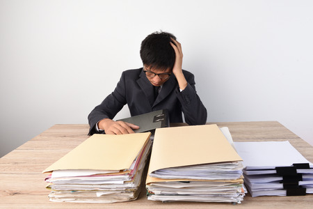 Businessmen sit stressed in the office because of busy work.の写真素材
