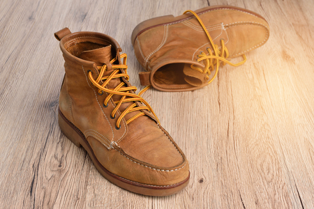 Brown leather boots on wooden floorの写真素材