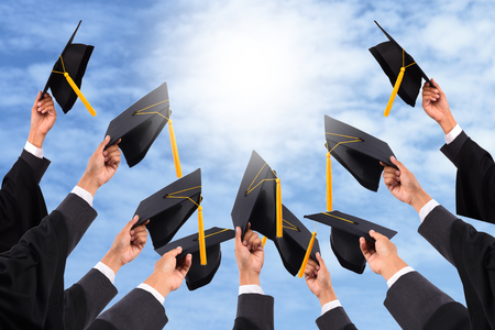 Graduates of the University,Of graduates holding hats handed to the sky.の写真素材