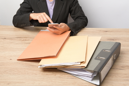 Working women check email through phone,File Stack top view, file folder pace on wood desk backgroundの写真素材