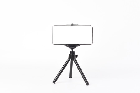 Mobile phone set on tripod for taking pictures,white isolated background.の写真素材
