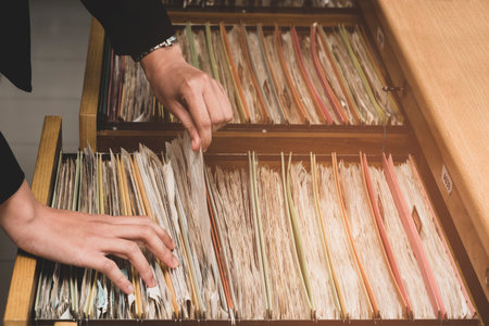 Woman working hand searching document in filing cabinet.