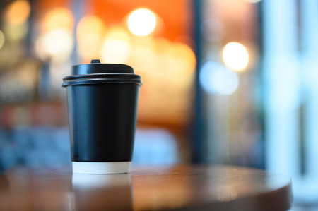 A cup of coffee on wooden table ready to take away for drink.の写真素材