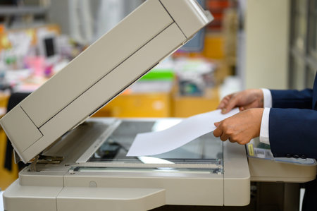 Employees are copying documents with a copy machine at the office.