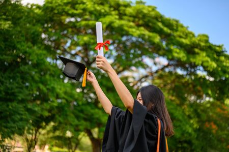 Long haired female students wearing black ruffle dresses expressing joy on graduation at the university.