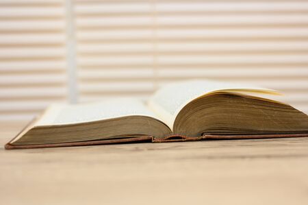 Old brown books open on a wooden tableの写真素材