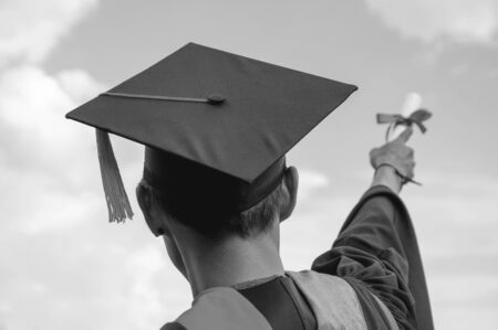 Male graduates hold a degree certificate to the sky.の写真素材
