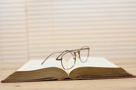 Old brown books open on a wooden tableの写真素材
