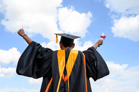 Male graduates hold a degree certificate to the sky.の写真素材